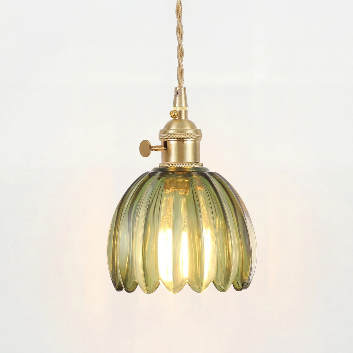 Blomformad pendellampa i glas som lyser med varmt diffust ljus