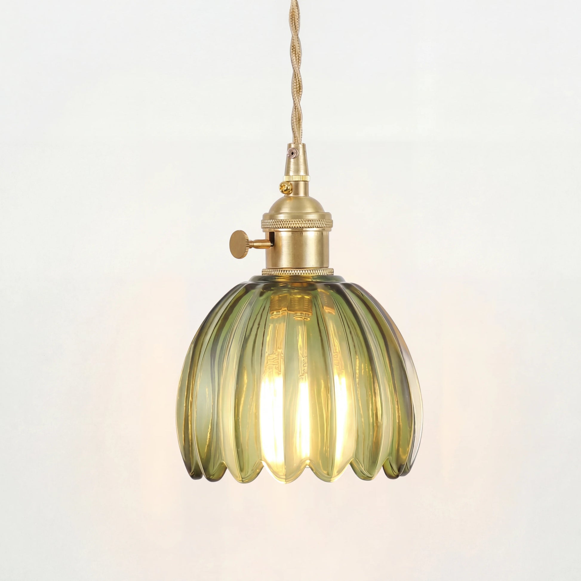 Blomformad pendellampa i glas som lyser med varmt diffust ljus