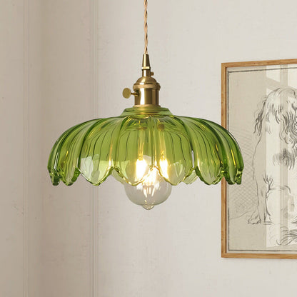Pendellampa i färgat munblåst glas med mässingsdetaljer, tänd över matplats